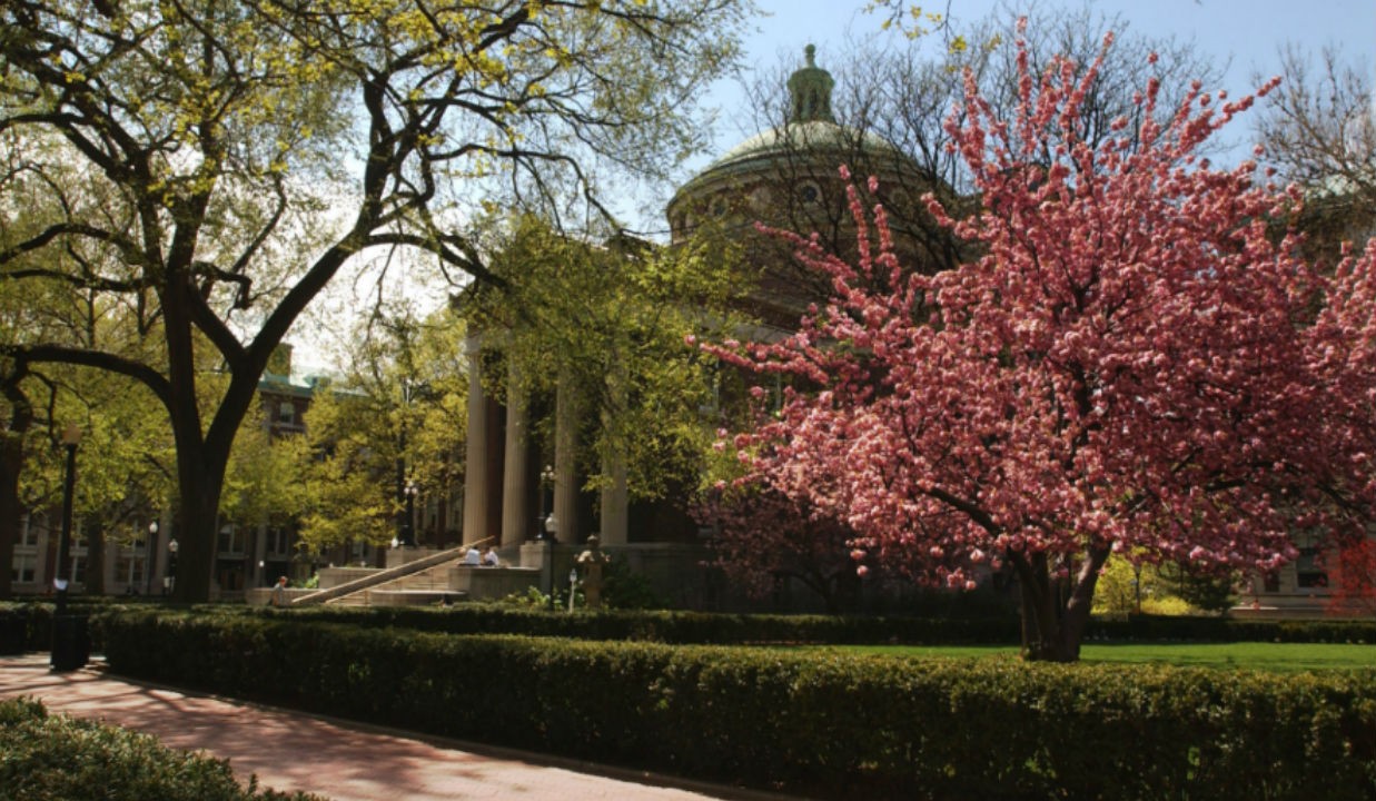 Earl Hall in backdrop of red and green leafy trees